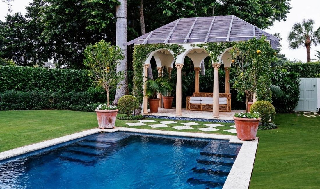 A Palm Beach property with an outdoor covered gazebo or pergola covered in a green vine.
