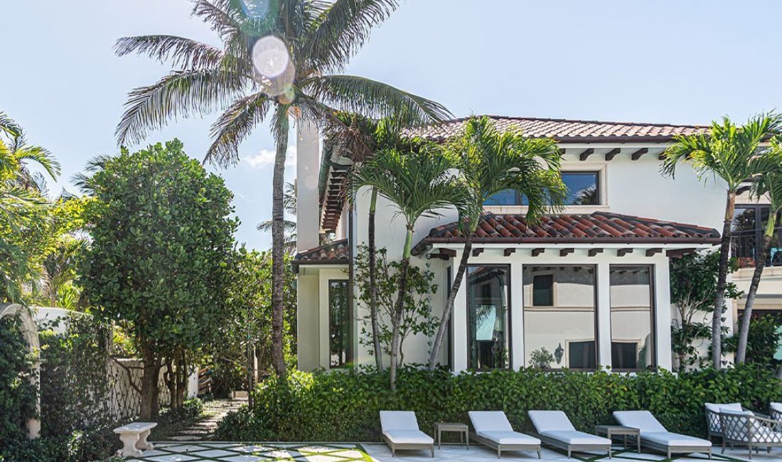 A Palm Beach property with a variety of trees near a building and outdoor pool.