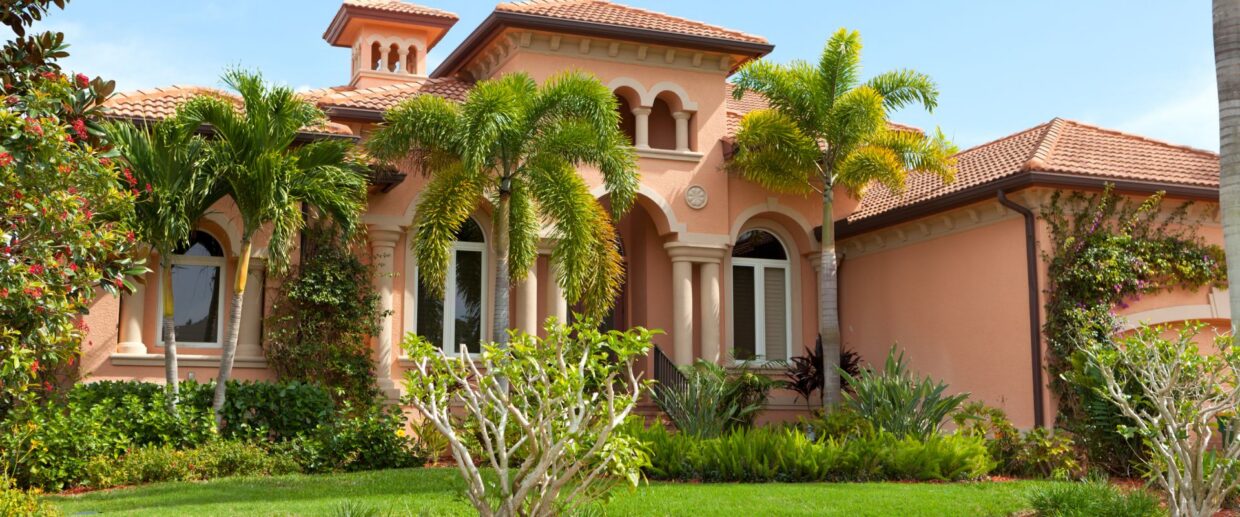 Mediterranean-style Palm Beach estate with manicured lawn, tropical palms, and professional landscape maintenance by Coastal Gardens.