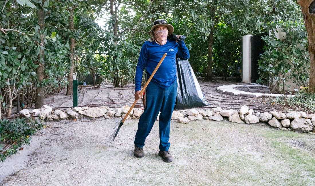 A Coastal Gardens employee carries a trash bag and a rake to clean up yard debris.