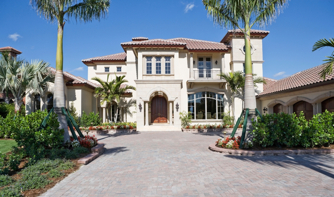 Elegant outdoor seating area beneath mature date palms at a Palm Beach home, highlighting how protected palms enhance outdoor living through the winter season. 